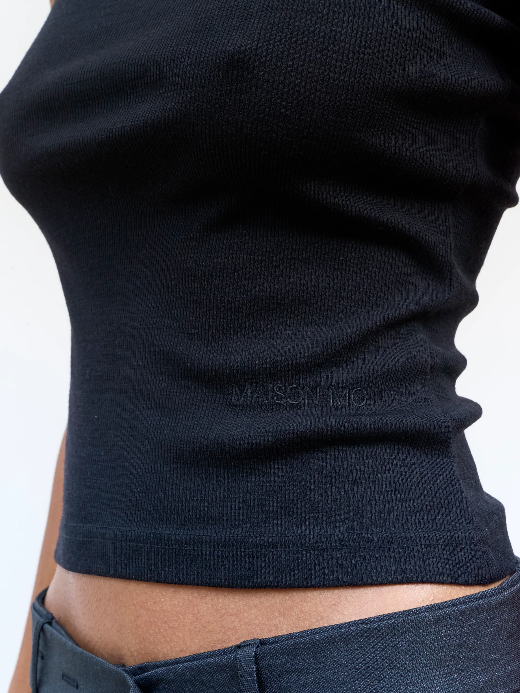 Black fitted tank top in Gorgonian Black, detail showing black ribbed tank top hem with Maison Mo embroidery